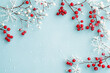 © Mattie - Merry Christmas and Happy Holidays greeting card, frame, banner. New Year. Copy space.  Berries, branches, snowflakes on light blue background top view. Winter xmas holiday theme. Flat lay