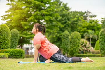 Overweight Asian women practice yoga in the park to strengthen their body and help them lose weight.Young woman is happy to motivation exercise or outdoor in the garden to control or lose weight