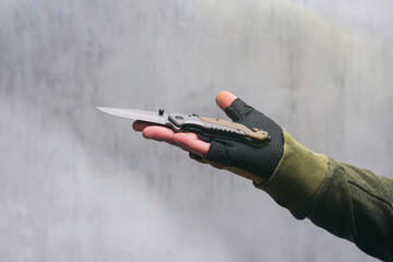 Male military man holding a tactical knife in his hand. Soldier with tactical brown gloves.