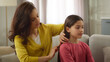 © Yuliia - Smiling friendly family Caucasian sisters woman female mother sister babysitter combing brushing hair make hairstyle coiffure talking with little girl sibling child kid daughter sit living room home
