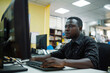 © Татьяна Евдокимова - Ivorian it professional is concentrating while typing on a keyboard and working at his computer in a modern office