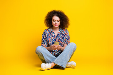 Canvas Print - Full length photo of lovely young lady sit floor hold device dressed stylish colorful garment isolated on yellow color background