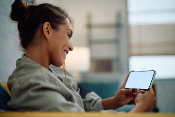 Happy woman watching something cell phone while relaxing at home.