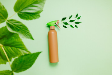 Empty bottle with organic cleaning spray and fresh plant leaves on green background, top view. Eco friendly home cleaning product, kitchen and bathroom detergent