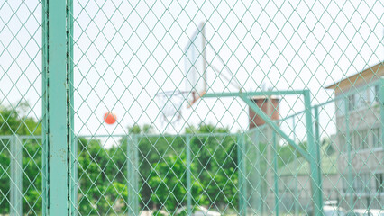 Active young male playing street basketball, dribbling ball, training on court