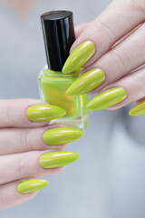 Wall Mural - Female hand with long nails and yellow green manicure