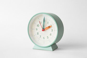 Wall Mural - green round alarm clock with text hours and minutes on the clock hands on white background, copyspace. pastel color