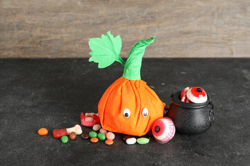 Wall Mural - Paper pumpkin for Halloween and tasty candies on dark table