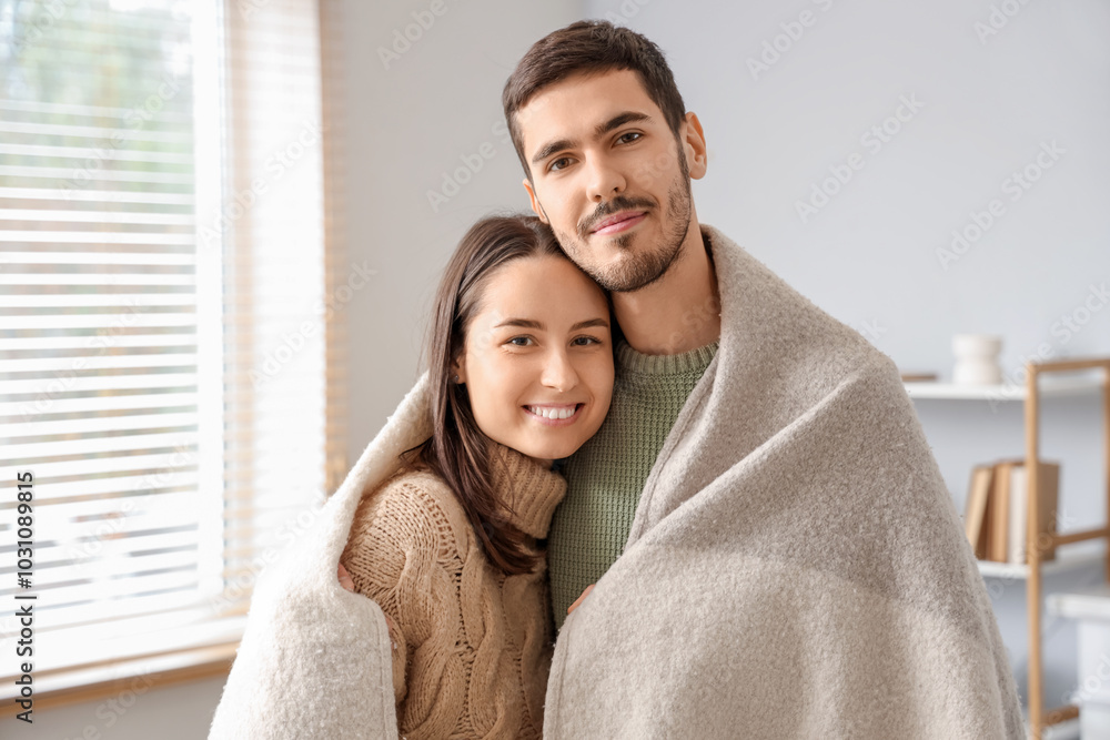Loving couple with warm plaid at home on winter day