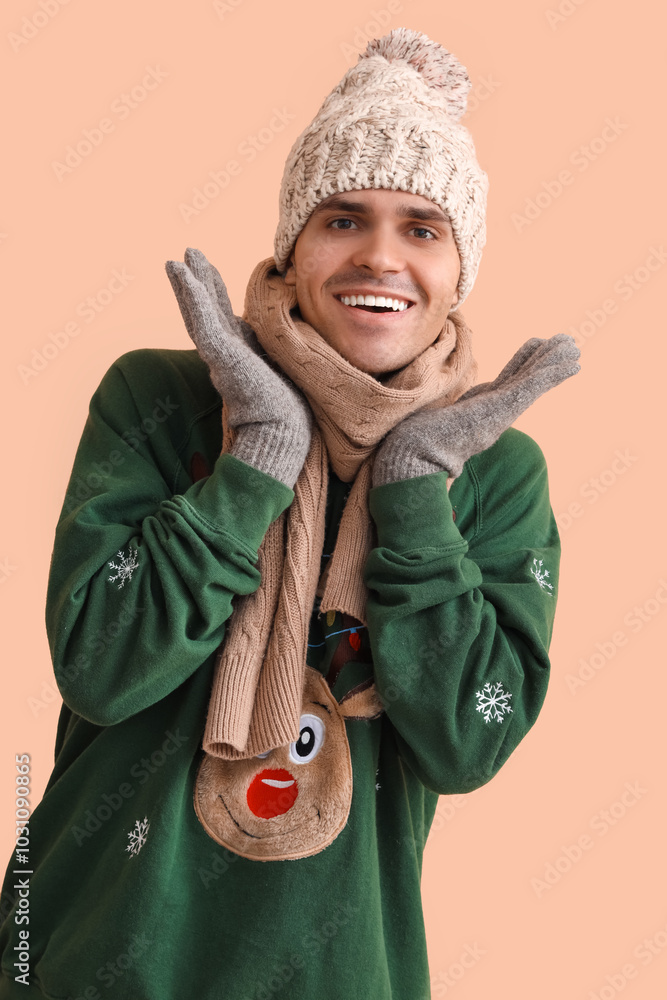 Young man in Christmas sweater on beige background