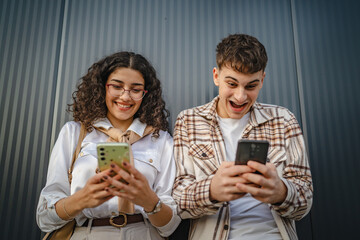 Young couple use mobile phone for explore internet front black wall