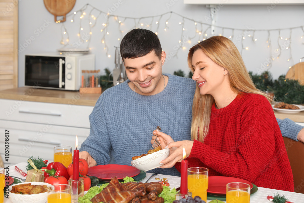 Young couple having Christmas dinner at table in kitchen