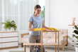 © New Africa - Young woman cleaning wooden shelf with rag at home