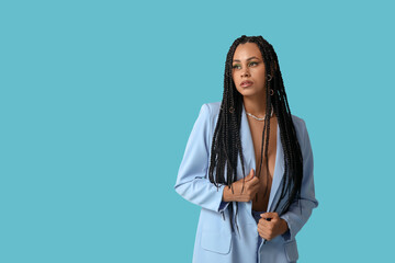 Wall Mural - Sexy young African-American woman with braids on blue background