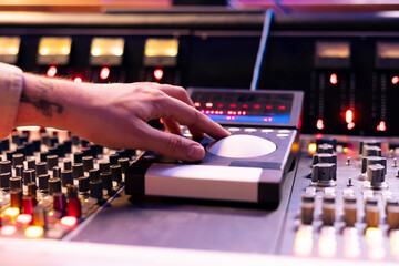 Fototapete - Skilled sound engineer operating mixing console and motorized faders in studio, using technical equipment to edit and process new tracks in control room. Young composer producing songs. Close up.