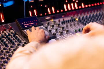 Fototapete - Tracking engineer pressing faders and buttons on control desk to balance sounds and add effects in post production, creating new music. Technical expert working with sliders in professional studio.