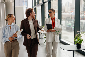 A diverse team is actively discussing innovative ideas together in a modern office space with large windows