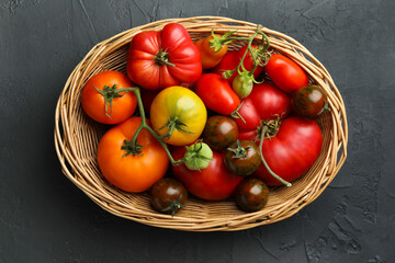 Poster - Different ripe and unripe tomatoes in wicker basket on grey textured table, top view