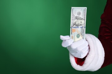 Santa Claus holding dollar banknotes on green background, closeup. Space for text