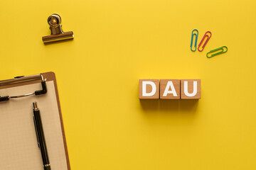 There is wood cube with the word DAU. It is an abbreviation for Daily Active Users as eye-catching image.