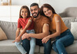 © Prostock-studio - Coronavirus Vaccination Advert. Happy Vaccinated Family Of Three People Showing Arm With Sticking Plaster After Covid-19 Vaccine Vax Injection Posing Sitting On Couch In Living Room, Smiling To Camera