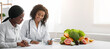 © Prostock-studio - Cheerful african woman nutritionist making treatment plan for female patient, clinic interior