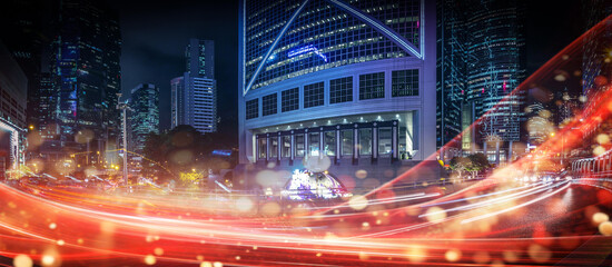 Canvas Print - Night time cityscape of Hong Kong, China showing high rise buildings with a tunnel and road with streaks of car lights.