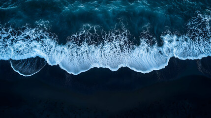 Canvas Print - Aerial view of ocean waves crashing onto a dark sandy shore.