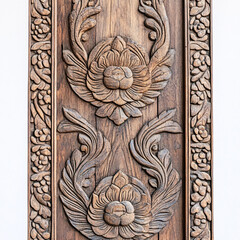 ornate wood carving of floral motifs on a wooden doorway in brown tones