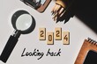 © Debalina - Looking back at the year 2024 concept with wooden chips and inscription. Best of the year, highlights, review, performance, evaluation of 2024. Office desk background.