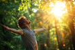© Pramesti - Young man with arms outstretched, embracing the warm sunlight in a lush green forest, experiencing a moment of peace and joy