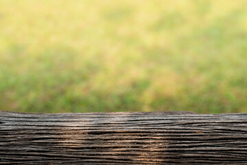 detailed grain pattern of weathered wooden table with blurred green grass meadow in the background, podium concept