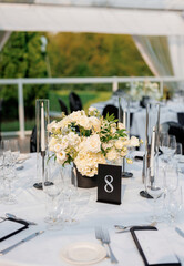 A set table in a restaurant number eight decorated with flowers and candles. A table in a restaurant overlooking the park. A restaurant with beautifully decorated tables awaiting guests