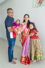 ndian family spending time together, wearing traditional and casual outfits with a baby, a young girl, and grandparents in a high-rise apartment in Kuala Lumpur, Malaysia.