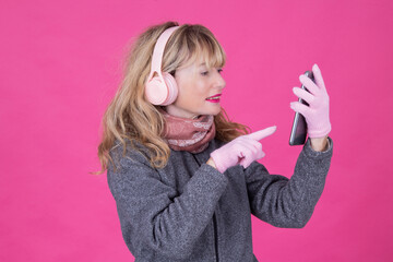 Mature woman with headphones on pink background