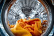 © Di Studio - inside view of a washing machine with water and orange towel