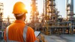 © Phirakhup - Worker in safety gear inspecting industrial site at sunset.