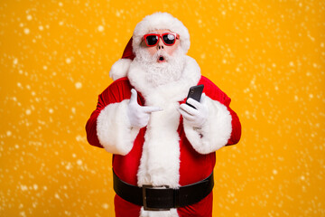 Portrait of his he nice attractive amazed fat overweight bearded Santa demonstrating device gadget web service shopping order delivery isolated bright vivid shine vibrant yellow color background