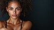 ©  Jovaduplex - An elegant woman with curly hair and striking freckles poses in a poised manner, wearing a black tank top, exuding confidence and grace against a dark background.