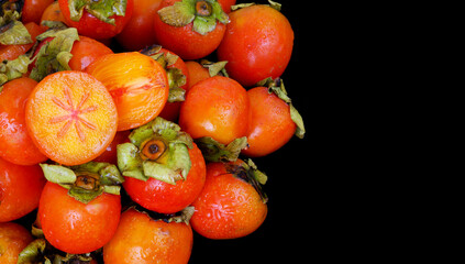 Wall Mural - Wet persimmon fruits isolated on black background. Copy space for text.	