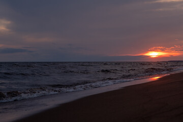 Poster - Golden hues reflect on the wet sand as the sun sets beyond the horizon, creating a peaceful ambiance on the beach