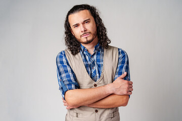 Wall Mural - A confident young man with curly hair poses against a neutral backdrop