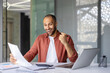 © Liubomir - Happy businessman showing excitement at desk with laptop and documents, feeling success and anticipation in business environment. Bright smile reflects achievement and satisfaction.
