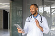 © Liubomir - Professional doctor wearing stethoscope having friendly video call on tablet. Smiling and gesturing, showcasing modern healthcare communication and digital interaction in medical environment.