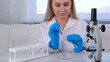 © Евгения Медведева - professional scientist takes a sample for a medical experiment. A research chemist works in a laboratory with a micropipette and a microscope