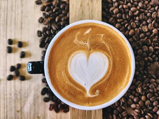 Heart coffee latte art milk foam on cup and coffee beans