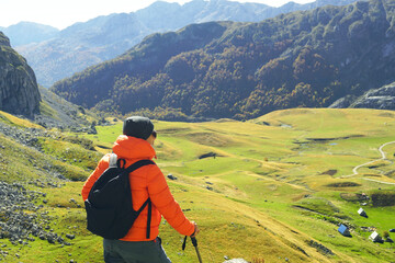 Wall Mural - A man stands on the top and enjoys the autumn landscape. Trekking in beautiful places of Montenegro: a tourist against the backdrop of a colorful valley and picturesque mountains near Kapetanovo Lake