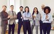 © Studio Romantic - Group portrait of happy multiethnic united team in office applauding welcoming new coworker, successful employees standing together meeting in workspace, business colleagues looking at camera smiling