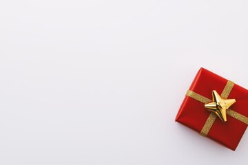 A single wrapped present with red paper and a gold bow, isolated on a pristine white background