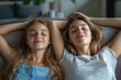 © Raool - Calm mom and daughter relax on couch hands over head, lying on sofa resting with eyes closed, mother chilling with teenage girl, Generative AI